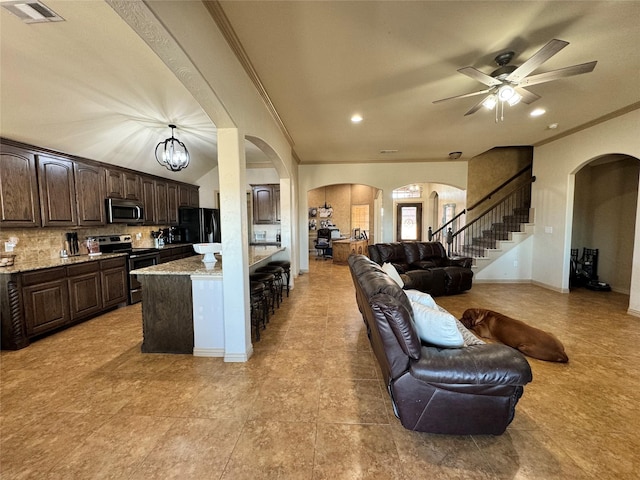 kitchen with tasteful backsplash, dark brown cabinets, ornamental molding, pendant lighting, and stainless steel appliances