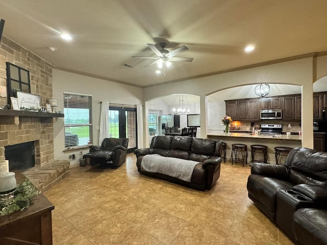 living room with crown molding, a fireplace, and ceiling fan with notable chandelier