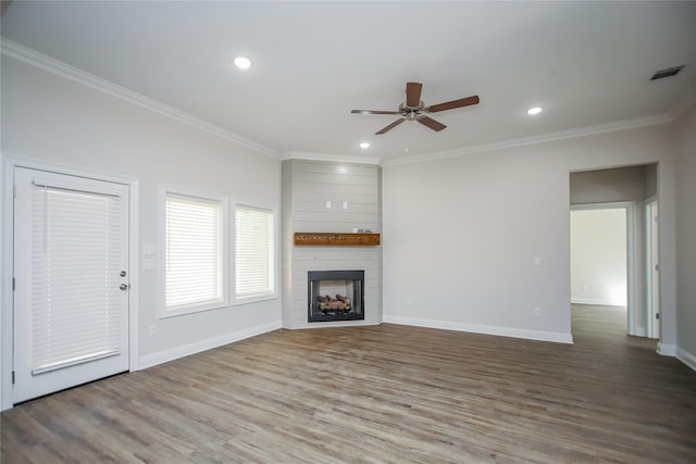 unfurnished living room featuring crown molding, wood-type flooring, a large fireplace, and ceiling fan