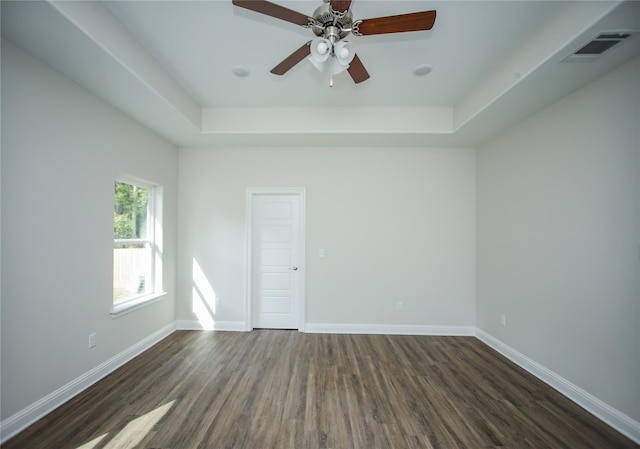 unfurnished room with a raised ceiling, dark wood-type flooring, and ceiling fan