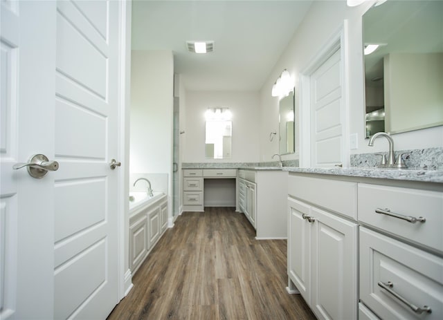 bathroom with hardwood / wood-style floors, vanity, and a bath