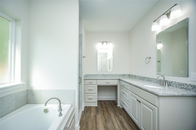 bathroom with vanity, hardwood / wood-style flooring, and a tub