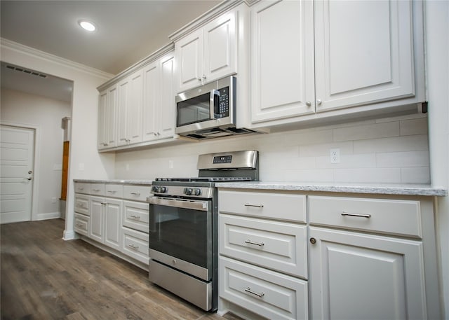 kitchen featuring white cabinetry, ornamental molding, appliances with stainless steel finishes, dark hardwood / wood-style flooring, and backsplash