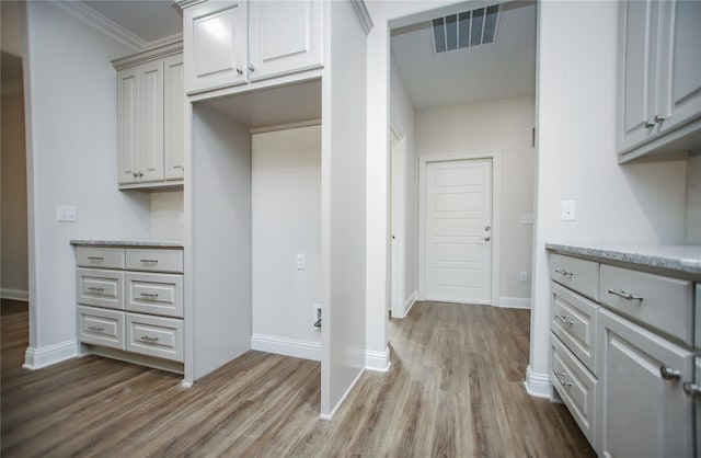 kitchen featuring ornamental molding, gray cabinetry, and light hardwood / wood-style flooring