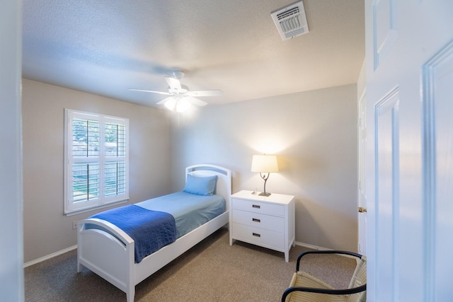 bedroom with ceiling fan, light colored carpet, and a textured ceiling