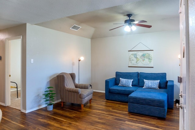 living room with a textured ceiling, dark wood-type flooring, and ceiling fan