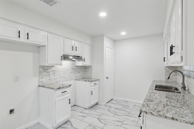 kitchen featuring white cabinetry, light stone countertops, and sink