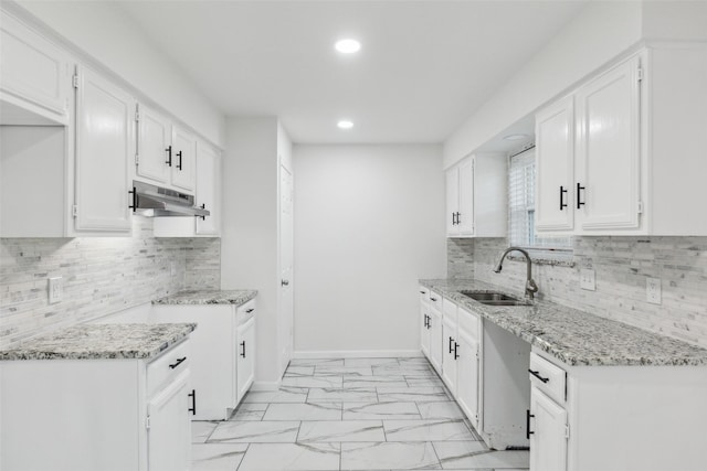 kitchen with tasteful backsplash, white cabinetry, light stone countertops, and sink