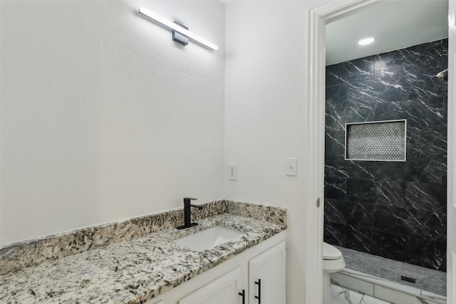 bathroom featuring vanity, toilet, and tiled shower