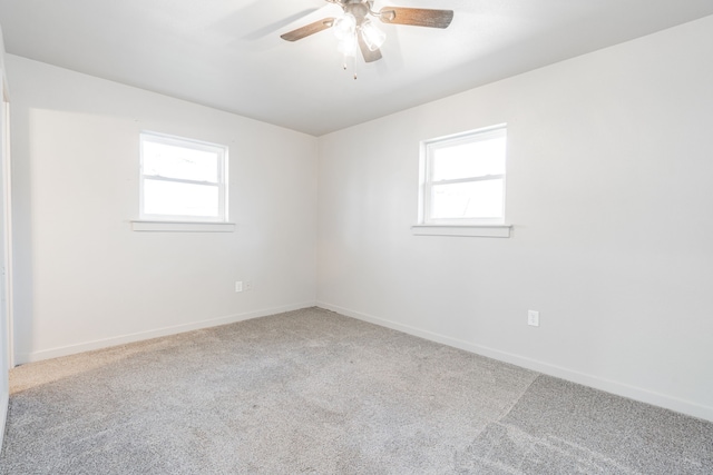 spare room featuring a wealth of natural light, ceiling fan, and carpet