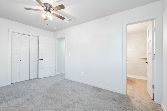 unfurnished bedroom with ceiling fan, light colored carpet, ensuite bath, and a closet