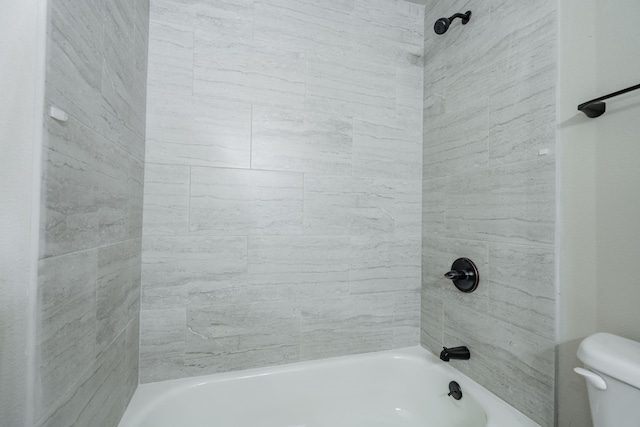 bathroom with toilet and tiled shower / bath combo