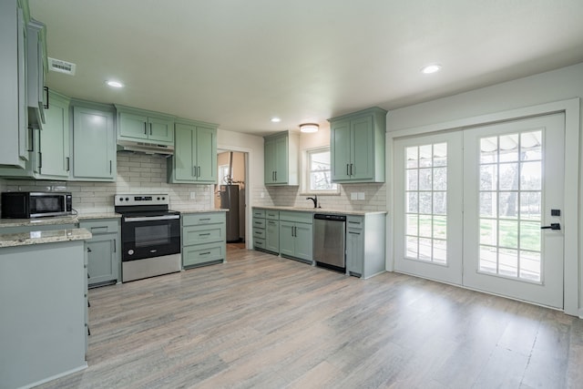 kitchen featuring decorative backsplash, light hardwood / wood-style flooring, stainless steel appliances, and green cabinetry