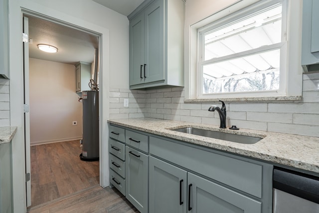 kitchen featuring sink, dark wood-type flooring, water heater, tasteful backsplash, and light stone countertops