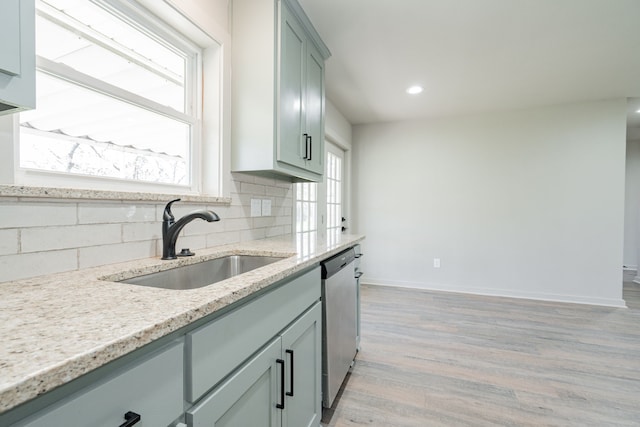 kitchen with sink, light hardwood / wood-style flooring, dishwasher, light stone counters, and decorative backsplash