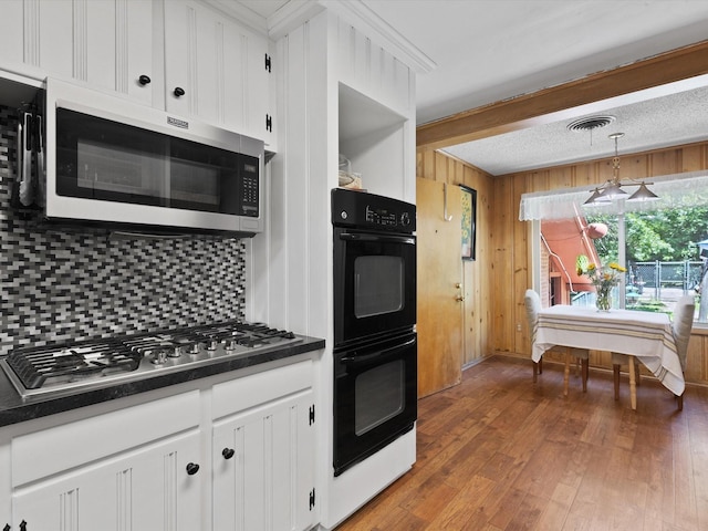 kitchen featuring white cabinetry, decorative light fixtures, dark wood-type flooring, and appliances with stainless steel finishes