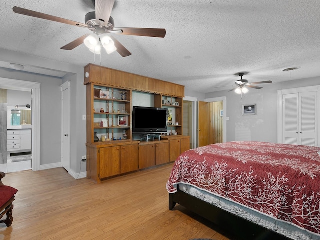 bedroom featuring ceiling fan, connected bathroom, light hardwood / wood-style floors, and a textured ceiling