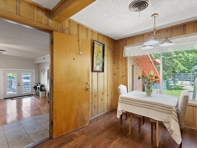 dining room with french doors, hardwood / wood-style floors, and wood walls