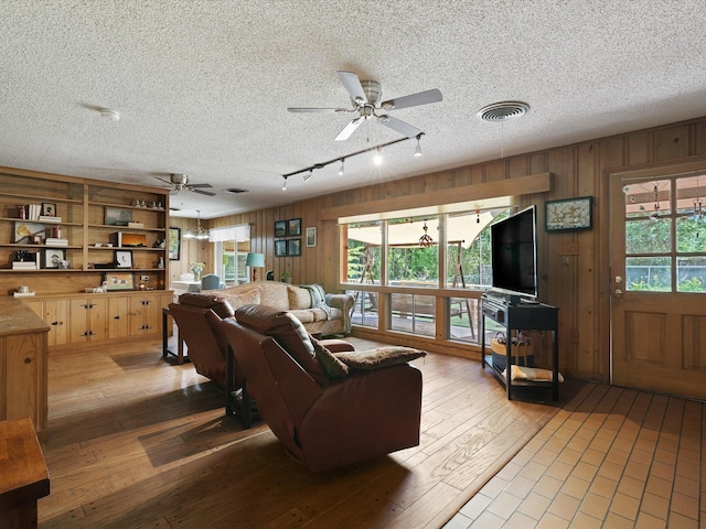 living room with hardwood / wood-style flooring, ceiling fan, and wood walls