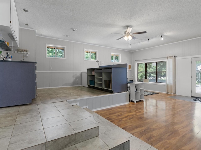 unfurnished living room with ceiling fan, ornamental molding, light hardwood / wood-style flooring, and a textured ceiling