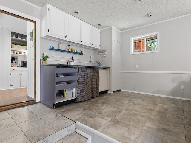 bar with white cabinetry, ornamental molding, sink, and a textured ceiling