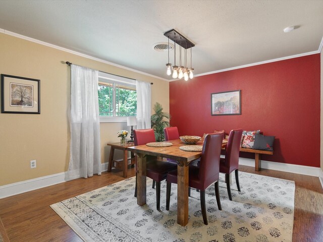 dining area featuring wood-type flooring and ornamental molding