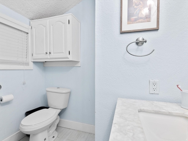 bathroom featuring vanity, toilet, and a textured ceiling