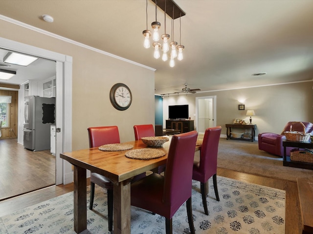 dining area with crown molding, a notable chandelier, and hardwood / wood-style flooring