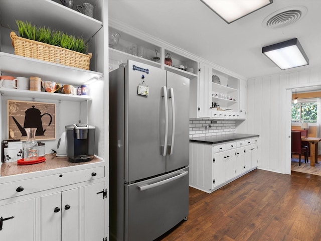 kitchen with tasteful backsplash, white cabinetry, dark hardwood / wood-style floors, and stainless steel refrigerator