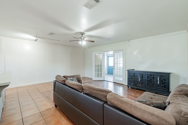 tiled living room with french doors, ceiling fan, and crown molding