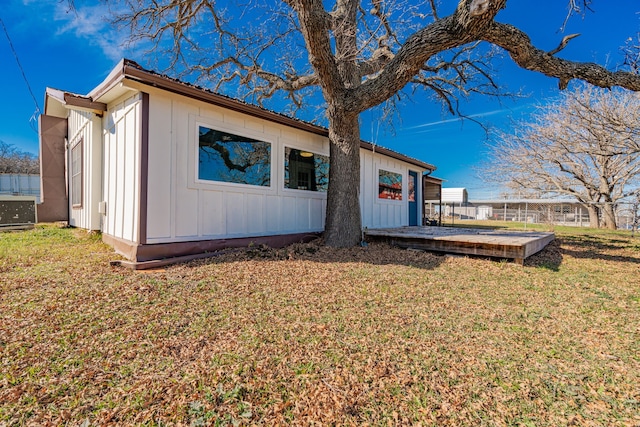 view of side of property featuring a wooden deck and a lawn