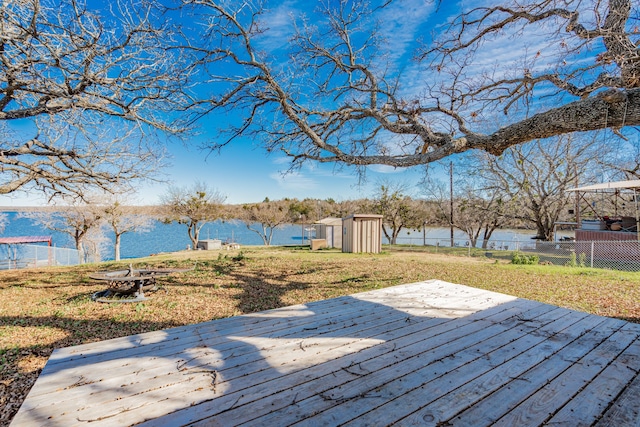 wooden deck with a shed, a yard, and a water view