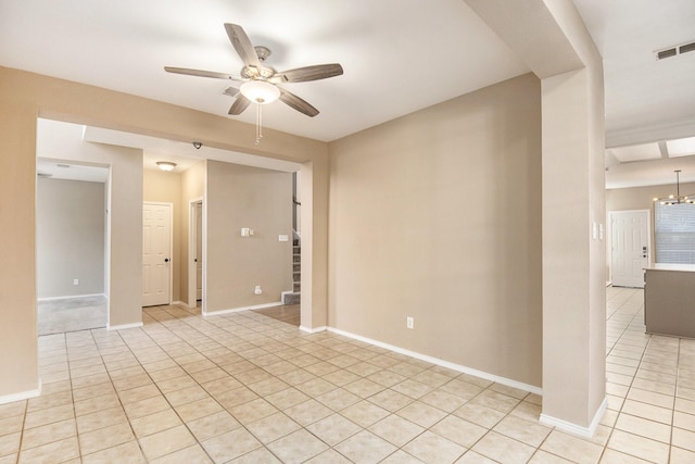 empty room featuring light tile patterned floors and ceiling fan with notable chandelier