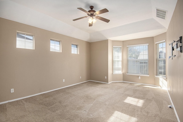 spare room featuring light colored carpet, ceiling fan, and a tray ceiling