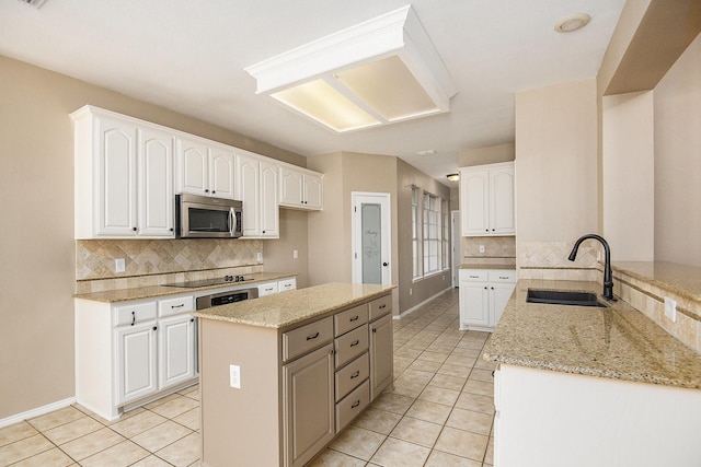 kitchen featuring light stone counters, white cabinetry, sink, and black electric cooktop