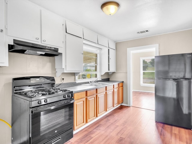 kitchen featuring black appliances, white cabinets, sink, and light hardwood / wood-style flooring