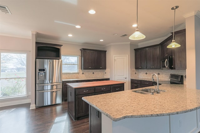 kitchen with decorative light fixtures, sink, kitchen peninsula, stainless steel appliances, and dark brown cabinets