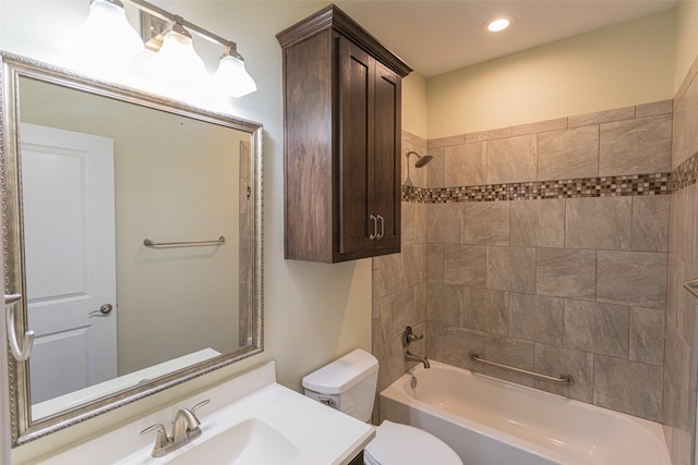 full bathroom featuring tiled shower / bath, vanity, and toilet