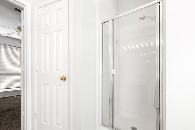 bathroom featuring ceiling fan and a shower with shower door