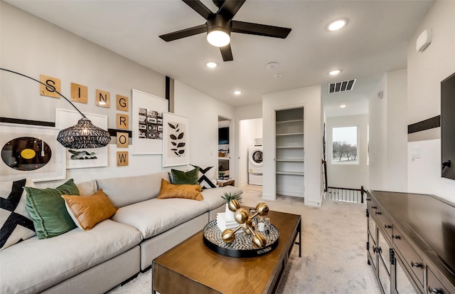 living room with washer / clothes dryer, ceiling fan, and light colored carpet