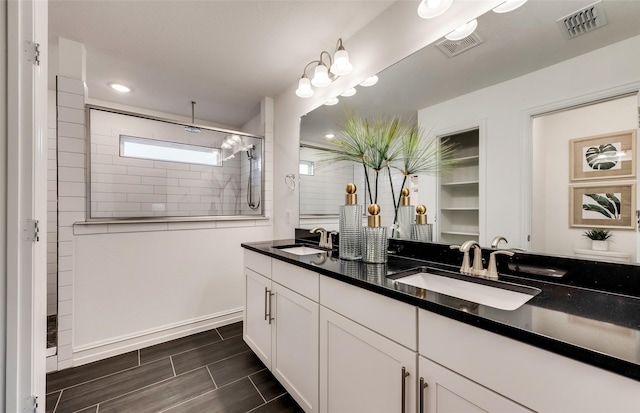 bathroom with a tile shower and vanity