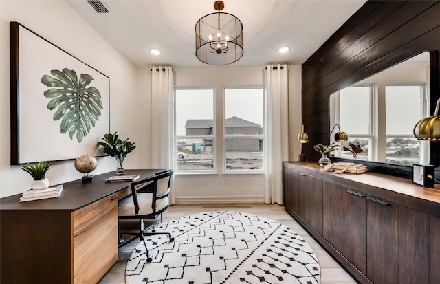 office space with light hardwood / wood-style floors, an inviting chandelier, and wood walls