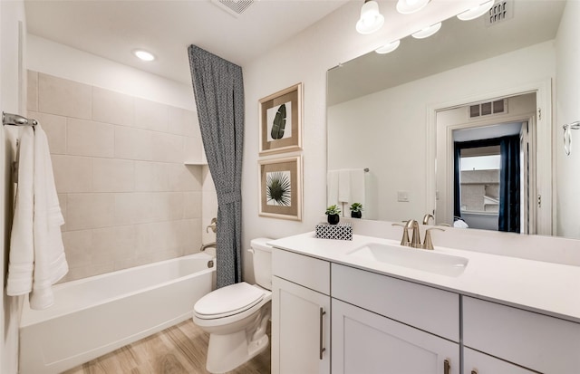 full bathroom with vanity, tiled shower / bath combo, hardwood / wood-style flooring, and toilet