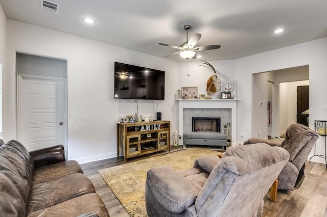 living room with ceiling fan, a fireplace, and wood-type flooring