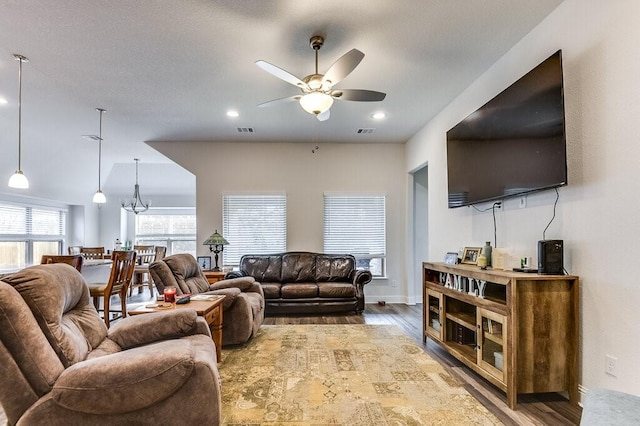 living room with wood-type flooring and ceiling fan with notable chandelier