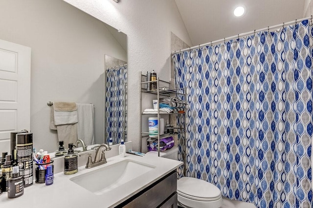 bathroom featuring lofted ceiling, vanity, toilet, and walk in shower