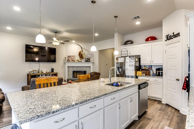 kitchen with appliances with stainless steel finishes, a kitchen island with sink, decorative light fixtures, white cabinets, and sink