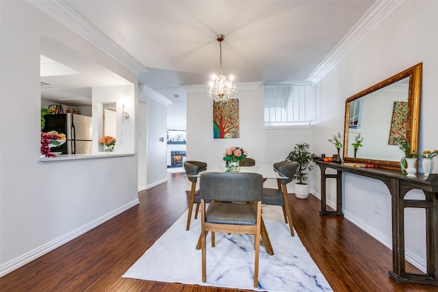 dining room with ornamental molding, dark wood-style flooring, a notable chandelier, and baseboards