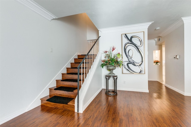 stairway featuring crown molding, visible vents, baseboards, and wood finished floors