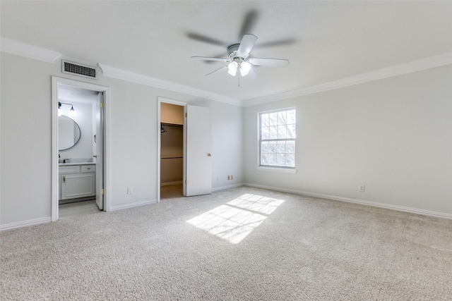 unfurnished bedroom with baseboards, visible vents, light colored carpet, ornamental molding, and a spacious closet